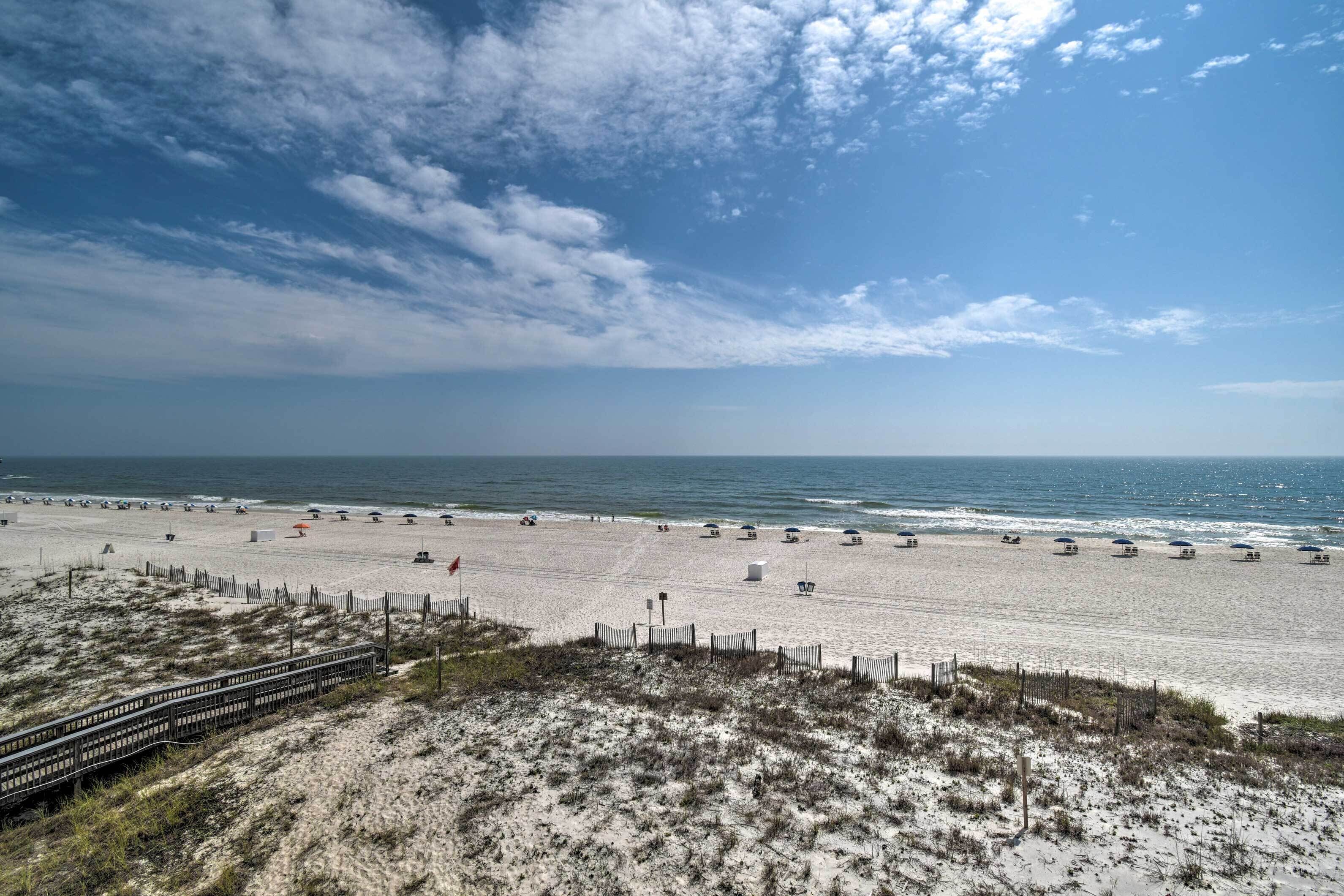 A beach with a wooden boardwalk leading to the shore, sandy beach, and ocean.