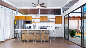 A modern kitchen with a central island, stainless steel appliances, and wooden cabinets. - Coral House, 5 min to the beach-  fiber optic internet and swimming pool  (Uvita)