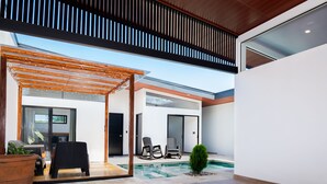 A modern outdoor patio with a wooden pergola, seating area, and a swimming pool. - Coral House, 5 min to the beach-  fiber optic internet and swimming pool  (Uvita)
