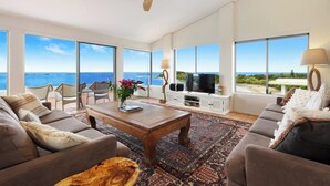 Un salón amplio con televisor grande, asientos cómodos y vista al océano.
