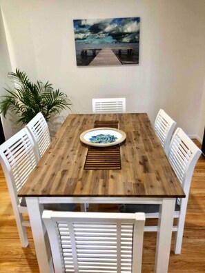 Enjoy meals in this dining area with a wooden table and six chairs, set with a plate and placemat.