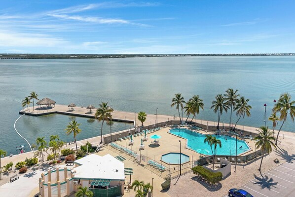 A resort with a large pool, palm trees, and a view of the water.
