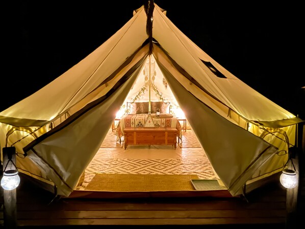 A tent with a bed and a table in the center, surrounded by a patterned floor. - 4200ft Luxury Stargazing Glamping Haven, Ultra-Private, Near BRP (Maggie Valley)