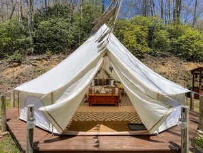 A tent with a bed inside, surrounded by a wooden deck and a patterned rug. - 4200ft Luxury Stargazing Glamping Haven, Ultra-Private, Near BRP (Maggie Valley)