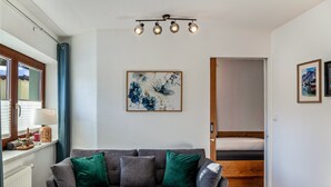 A modern living room with a grey sofa, a wooden door, and a framed floral artwork on the wall. - Apartment "Alpenrose" with Mountain View, Shared Terrace & Wi-Fi (Leutasch)