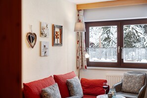 En hyggelig stue med en sofa, en lænestol og et bord med et glas.