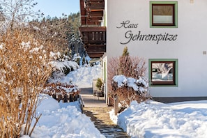 A snow-covered pathway leading to a building with the name 'Haus Gehrenspitze' on its facade.
