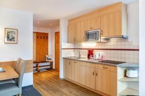 A compact kitchen with wooden cabinets, a microwave, a sink, and a toaster. - Apartment "Edelweiß" with Shared Garden & Wi-Fi (Leutasch)