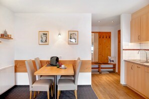 A compact kitchen with a wooden table and chairs, a bench, and a sink. - Apartment "Edelweiß" with Shared Garden & Wi-Fi (Leutasch)