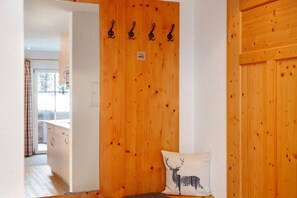 Una puerta de madera con un almohadón en silueta de ciervo, un perchero y una pequeña señal.
