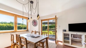 Un espace repas comprenant une table, des chaises et donnant sur l’extérieur.