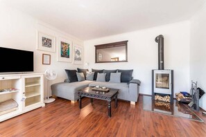 A living room with a sofa, coffee table, TV, fireplace, and artwork on the walls.