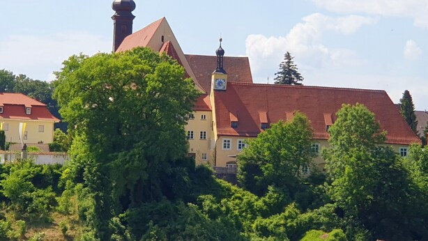 Un bâtiment doté d’une tour horlogée, d’un toit rouge et d’un clocher d’église.