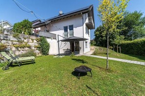 A two-story house with a balcony, a lawn, and a small patio area.