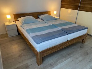 Un lit bien fait, avec un cadre en bois et une couvre-lit à rayures, deux tables de chevet avec des lampes et un plancher en bois.