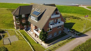 Une maison à deux étages avec un balcon, des panneaux solaires et une vue sur la mer.