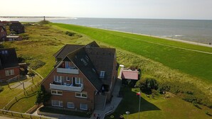 Une maison située sur la côte, dotée d’un balcon, d’une pelouse verdoyante et offrant une vue sur la mer.