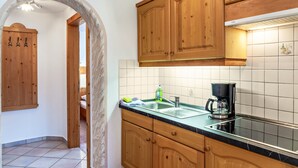 Une cuisine avec des meubles de rangement en bois, un plan de travail noir, un évier et une machine à café.