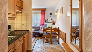 Une cuisine compacte avec des meubles en bois, un pare-feu en carreaux et un coin repas comprenant une banquette et des chaises.