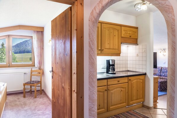 Una cocina con armarios de madera, una cafetera y vista a una montaña a través de una ventana.