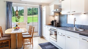 Eine moderne Küche mit Essbereich, großen Fenstern und Blick auf eine grüne Landschaft.
