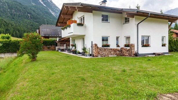 A two-story house with a balcony, a mountain in the background, and a well-maintained lawn. - Apartment "Bellamontes Apartment Top 2" with Mountain View, Balcony & Wi-Fi (Leutasch)