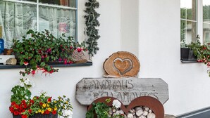 A building exterior with a sign reading 'Landhaus Blumovets,' potted plants, and a wooden heart-shaped decoration. - Apartment "Bellamontes Apartment Top 2" with Mountain View, Balcony & Wi-Fi (Leutasch)