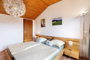 A bedroom with a wooden ceiling, a bed with two pillows, a nightstand, and a wall-mounted lamp. - Apartment 'Klug' with Mountain View, Private Terrace and Wi-Fi (Schonach im Schwarzwald)