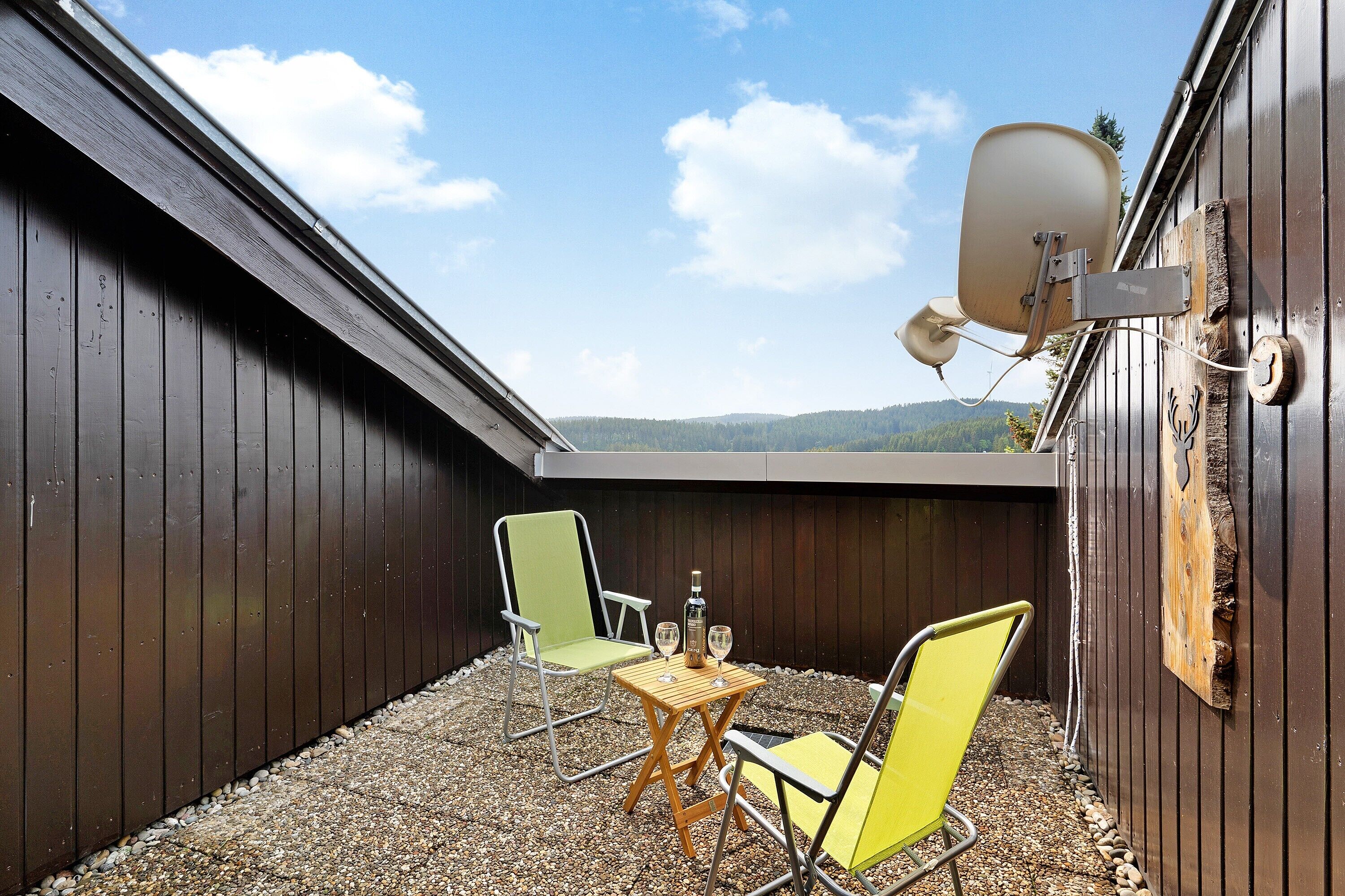 Une petite terrasse extérieure avec deux chaises, une table et une antenne parabolique.