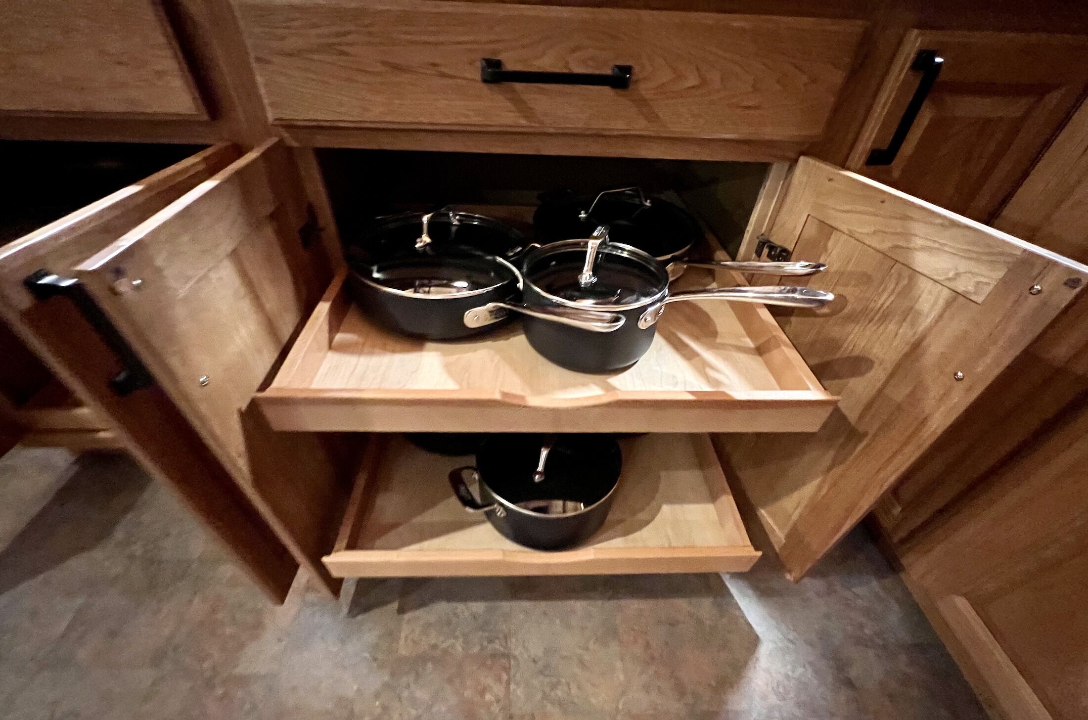 Una cocina con armarios de madera y un estante empotrado con ollas y sartenes.