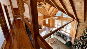 Interior de madera con techo alto, una escalera y un espacio de descanso con un árbol de Navidad.