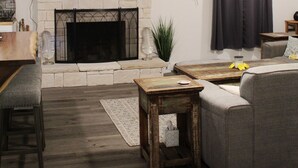 A living room with a fireplace, a television mounted on the wall, a ceiling fan, and a grey sofa. - Cozy lake house w/Lake Conroe access- pet friendly! (Montgomery)