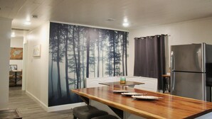 A modern kitchen with a wooden countertop, stainless steel refrigerator, and a large forest mural on the wall. - Cozy lake house w/Lake Conroe access- pet friendly! (Montgomery)