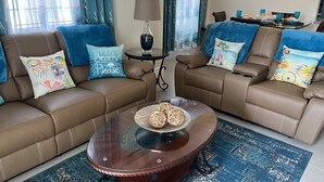 Un salon avec deux canapés en cuir marron, une table basse en verre et un tapis à motifs.