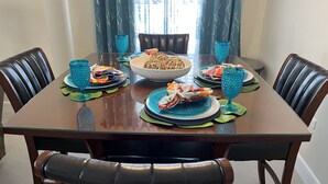 Une table à manger dressée avec des assiettes, des bols et de la verrerie bleue, entourée de chaises en cuir.