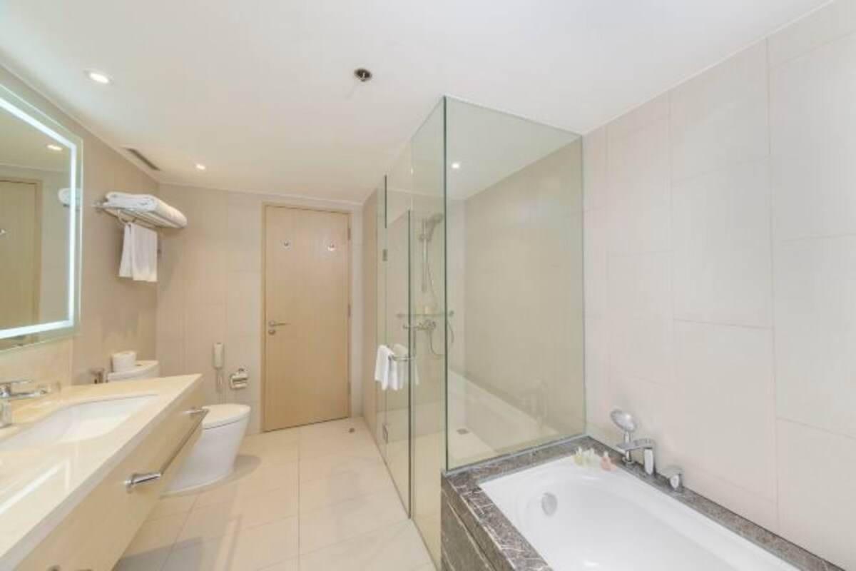 Un baño moderno con ducha envuelta en vidrio, una bañera grande e un lavabo doble con espejo.