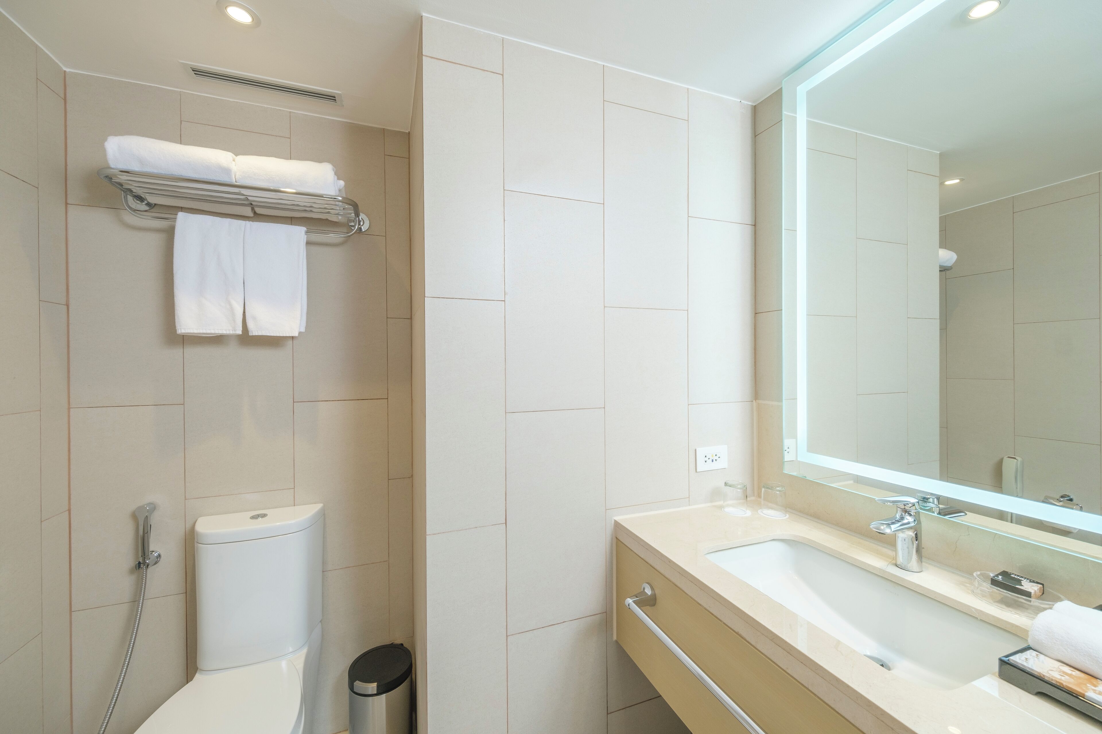 A modern bathroom with a toilet, sink, and mirror.