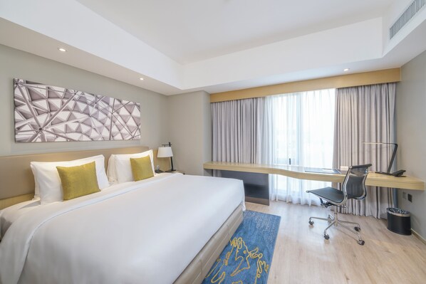 Una habitación de hotel moderna con una cama grande, un escritorio y una computadora.