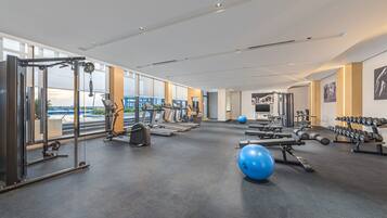 Un gimnasio amplio con máquinas de cardio, pesas libres y balones de ejercicio.