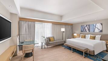 Ein modernes Hotelzimmer mit einem großen Bett, einem Schreibtisch, einer Couch und einem Fernseher.
