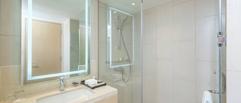 A modern bathroom with a large mirror, a sink, and a glass-enclosed shower area.