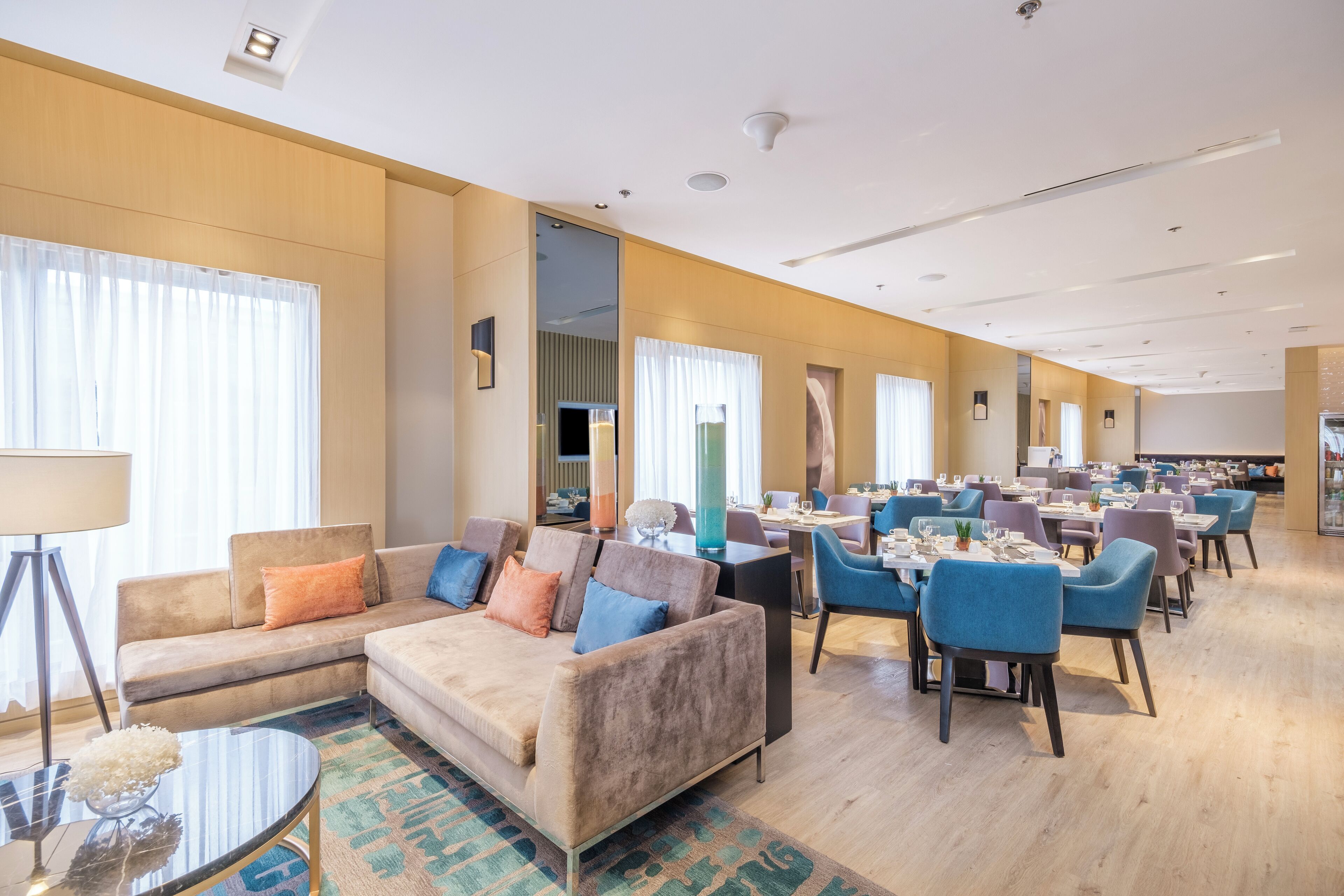 A hotel lobby with a sofa, dining area, and a view of the kitchen.