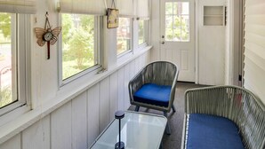 A room with a glass table, a wicker chair with a blue cushion, and a decorative butterfly wall hanging. - Warren Vacation Rental, Walk to Warren Town Beach (Warren)