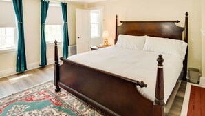 A large bed with a wooden frame, a patterned rug, and teal curtains. - Warren Vacation Rental, Walk to Warren Town Beach (Warren)