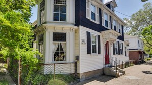 A two-story house with a red door and white trim, featuring a small porch and a brick section on the right side. - Warren Vacation Rental, Walk to Warren Town Beach (Warren)