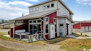 Une maison à deux étages dotée d’un patio couvert, d’un garage et d’une façade rouge et blanche.