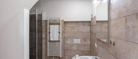 Un baño moderno con cabina de ducha de vidrio, un lavabo blanco y un perchero para toallas.