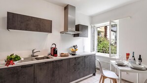 A modern kitchen with a large island, built-in oven, and a window overlooking greenery. - Serenata 5 - Cavigliano Studios with Terrace for 5, Cavigliano, Centovalli, Switzerland (Cavigliano, Centovalli)