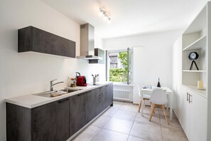 A modern kitchen with a built-in stove, a sink, and a dining area with a table and chairs. - Serenata 1 - Cavigliano, Cavigliano, Centovalli, Switzerland (Cavigliano, Centovalli)