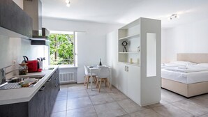 Cocina moderna con comedor, cama y vistas a la vegetación.